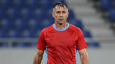 Middle-aged, muscular coach, mid-30s, waist-up, wearing a plain red and sky-blue training top (smooth polyester, split...