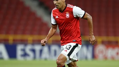 A photorealistic image of a 30-year-old, 5'9'' (175 cm) Necaxa player wearing a red jersey with white sleeves and white...