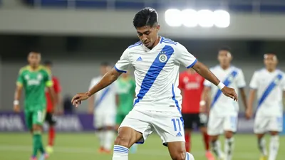 A tight action crop of a 25-year-old Mexican midfielder in a white jersey with a blue stripe, playing a one-two with a...