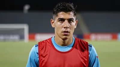 A determined 28-year-old Club Necaxa midfielder, athletic build, wearing a plain red and sky blue training top, against a...