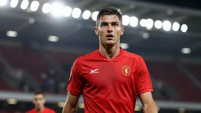 A mid-30s male midfielder in a solid red jersey, waist-up, intense expression, background blurred stadium lights