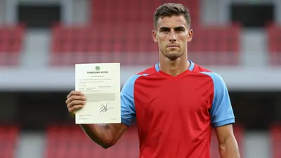 Mid-30s athletic midfielder, lean build, waist-up, intense gaze, holding a signed transfer document;