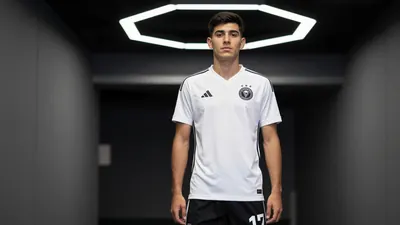 A 24-year-old Mexican center-back in a Sporting Kansas City jersey, with a clean white shirt and black shorts, standing...