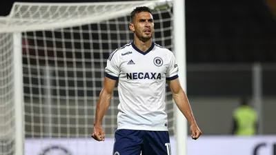 Waist-up shot of a muscular, 26-year-old forward wearing a Club Necaxa kit with deep blue shorts and a white jersey...